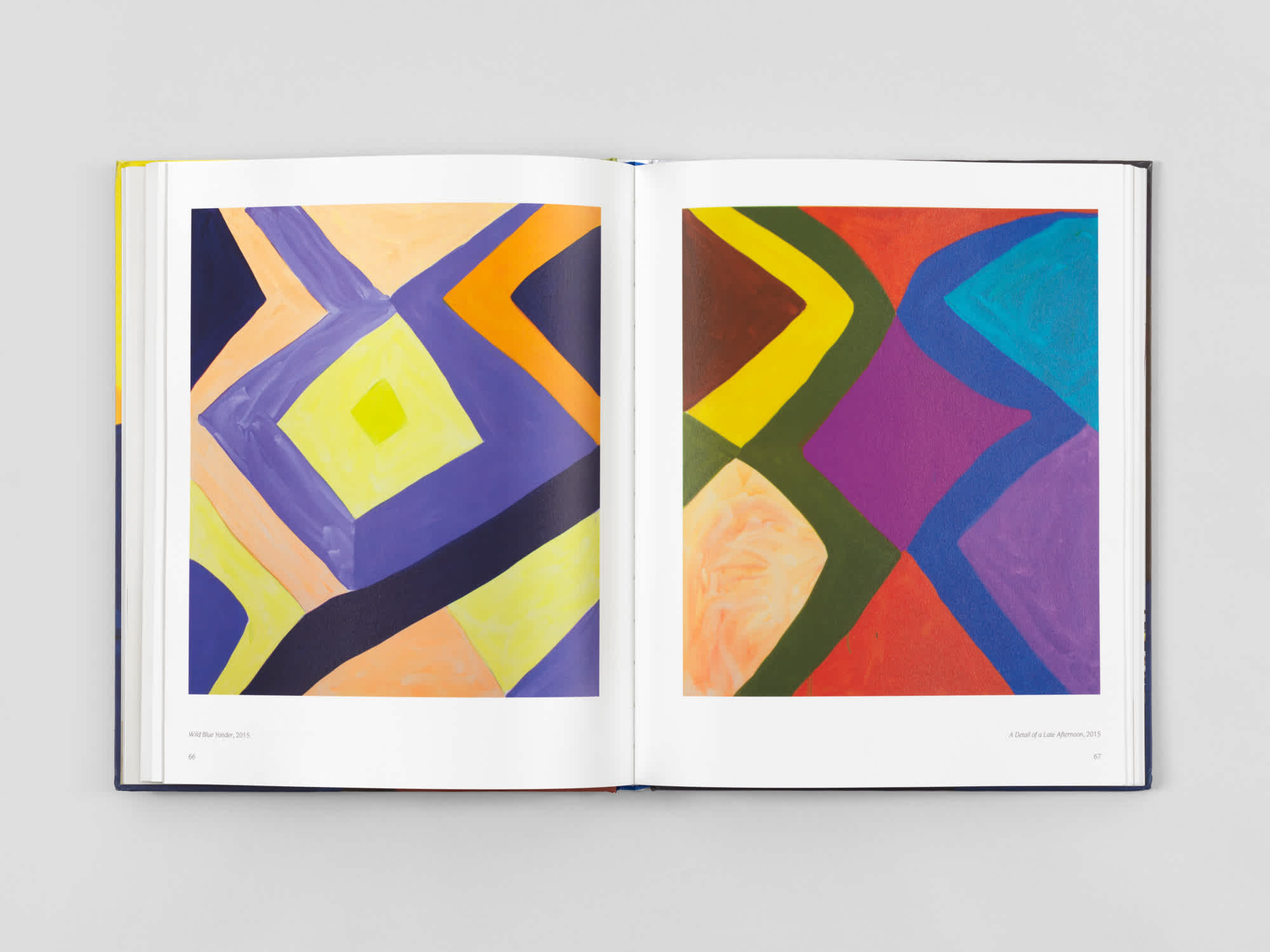 Two pages of an open book which each features a different colorful geometric painting.