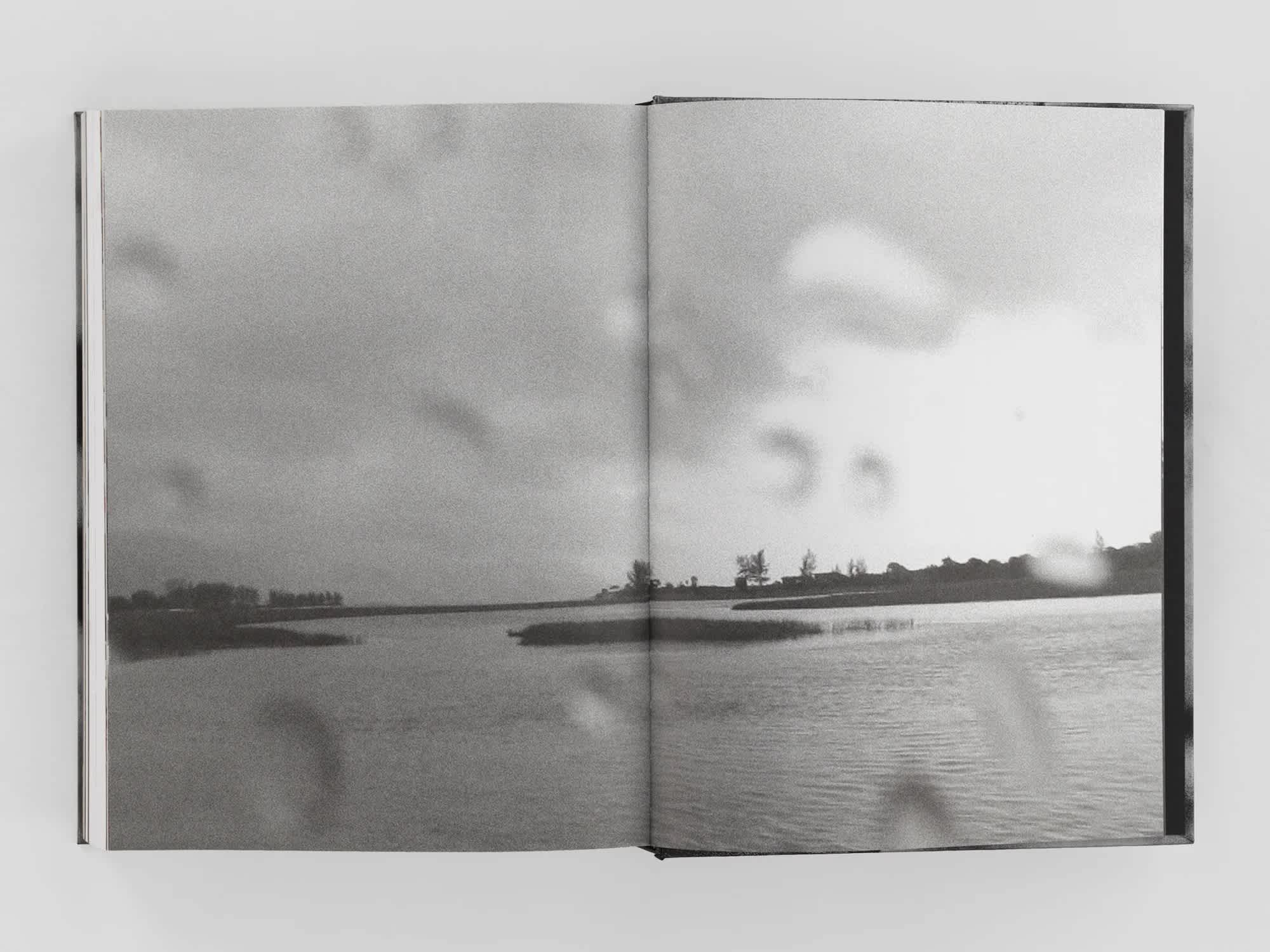 Open book with black and white full-bleed centerfold image of a waterway.