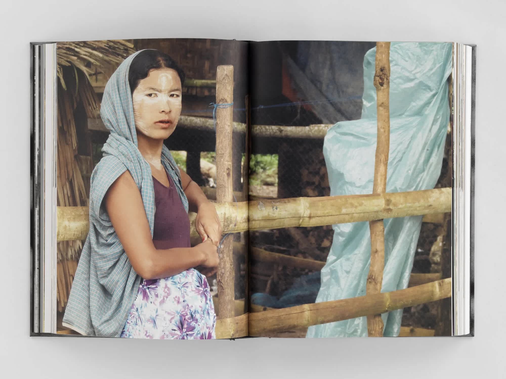 Open book with full-bleed centerfold image of a woman leaning against a fence wearing a shawl.