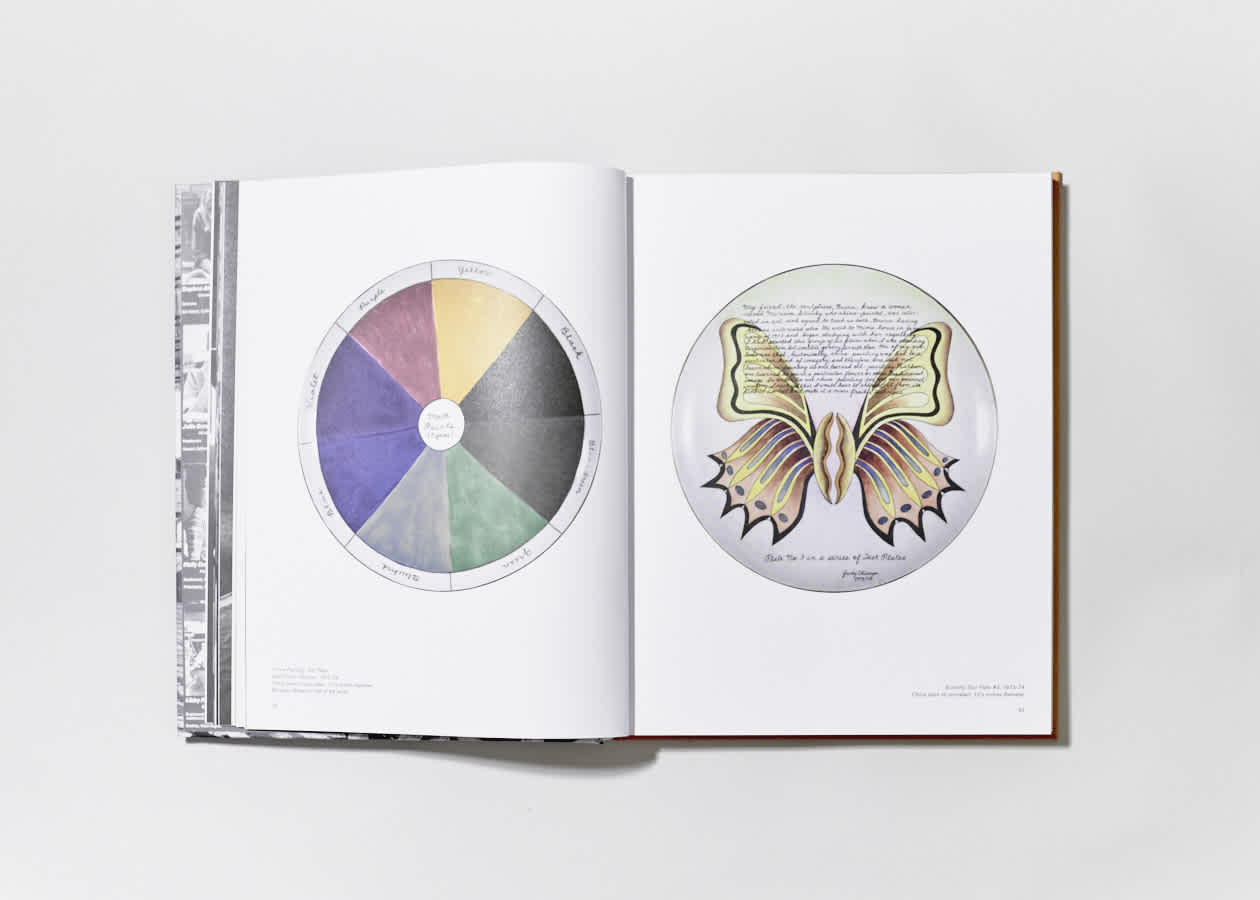 Open book with a dinner plate by Judy Chicago on each page. 