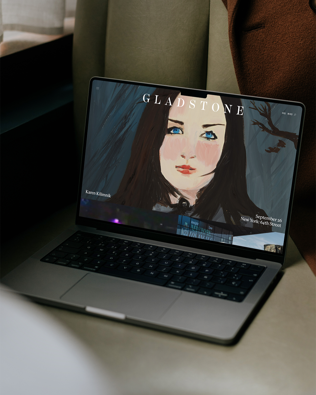 A laptop rests on a cushion, displaying the Gladstone website with digital artwork of a woman’s face, and exhibition details for Karen Kilimnik in New York.