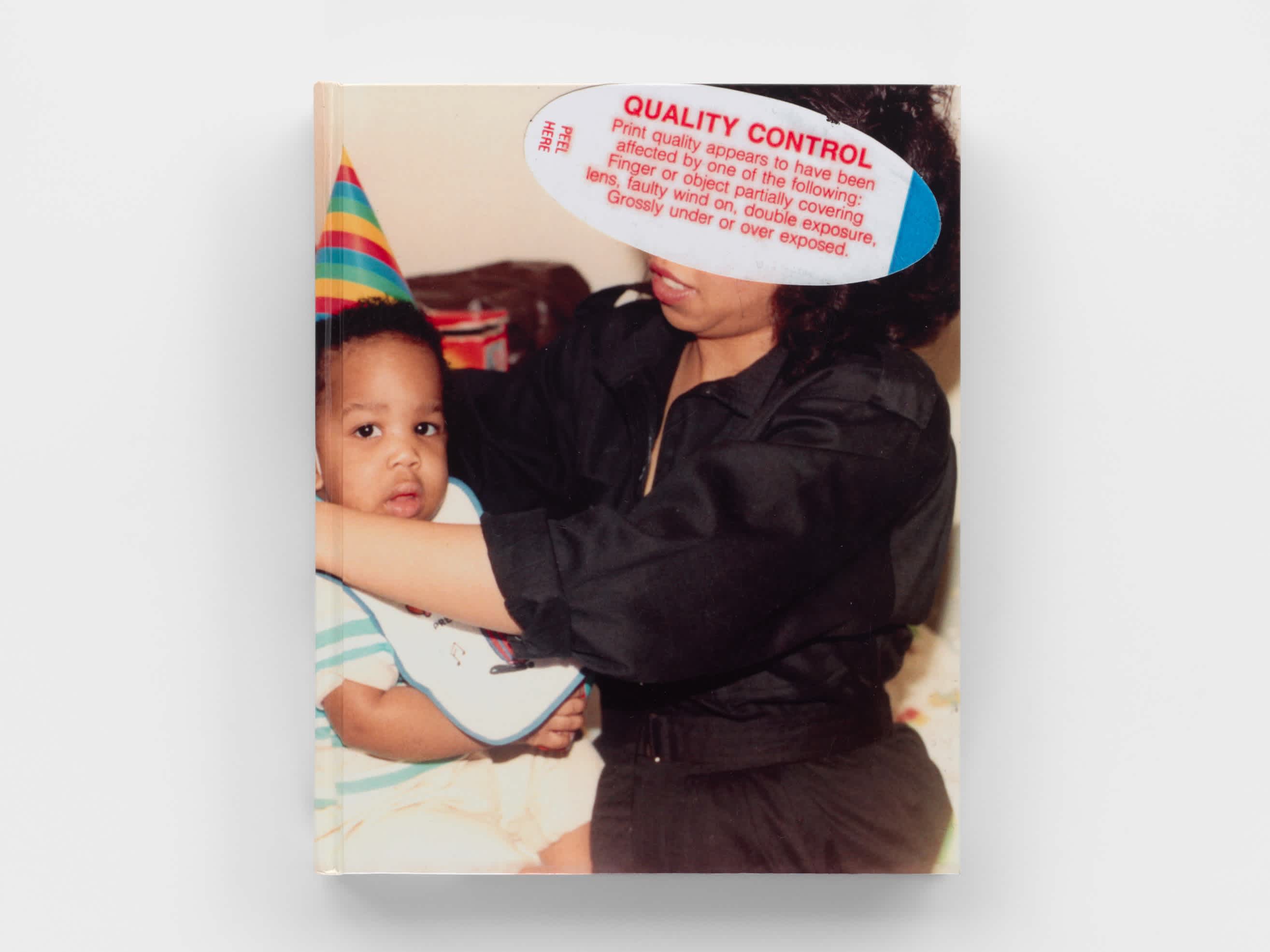 The front cover of a book floating on a gray background. The cover is an old home photo of a mother holding a baby. The baby wears a pointed birthday hat. The mother's face is obscured by a film processing quality check sticker which includes the title of the book, "Quality Control".