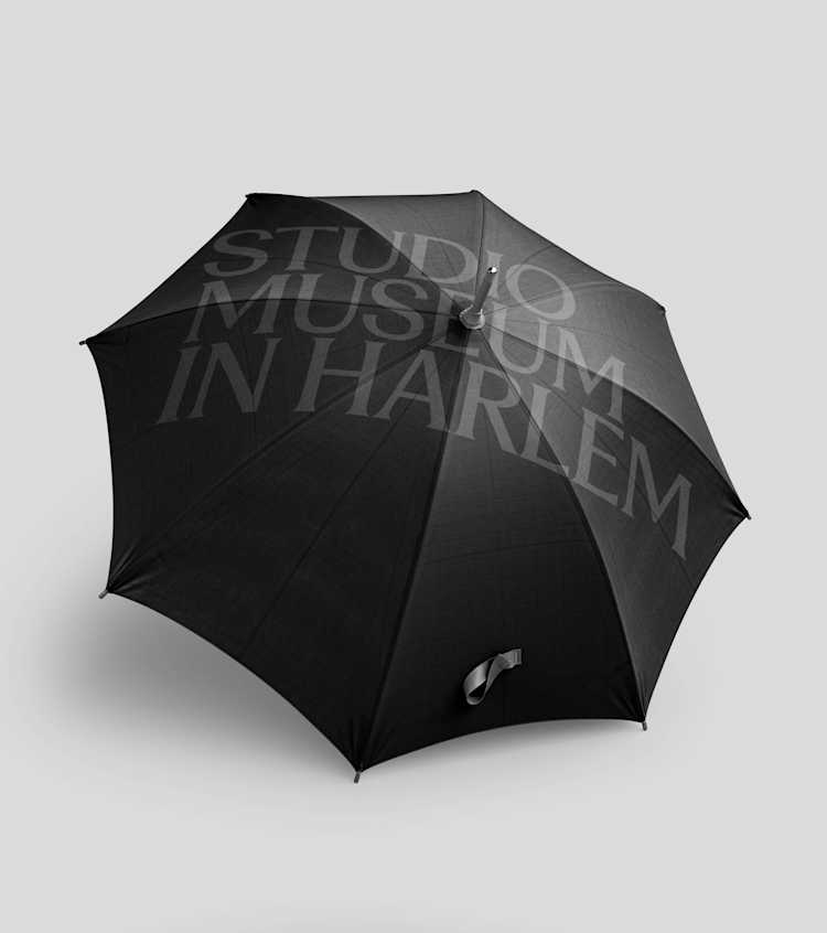 A black umbrella on a light gray background with the words STUDIO MUSEUM IN HARLEM printed in large, translucent letters across the top.