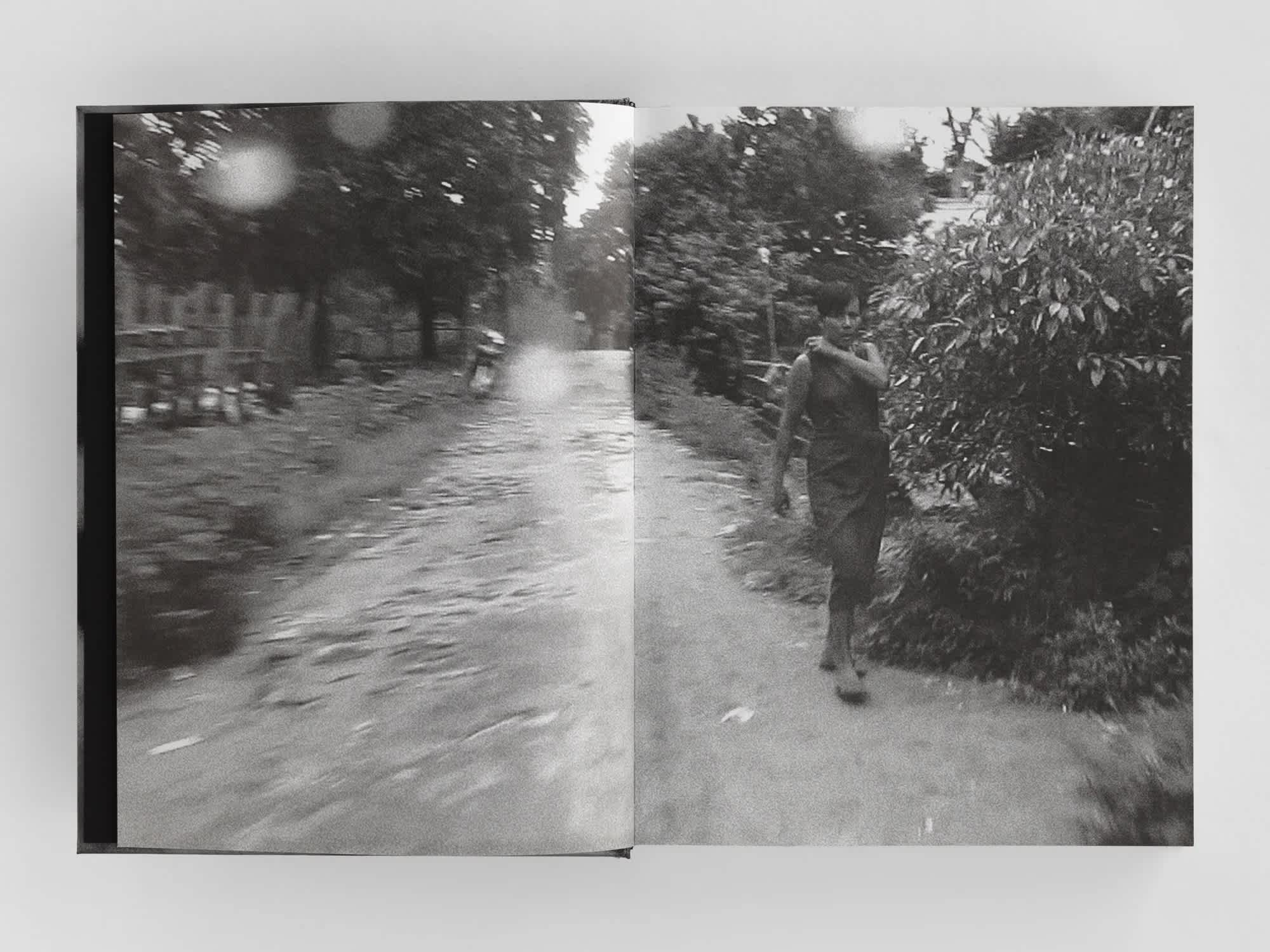Open book with full-bleed centerfold black and white image of a boy walking up a path towards the camera.
