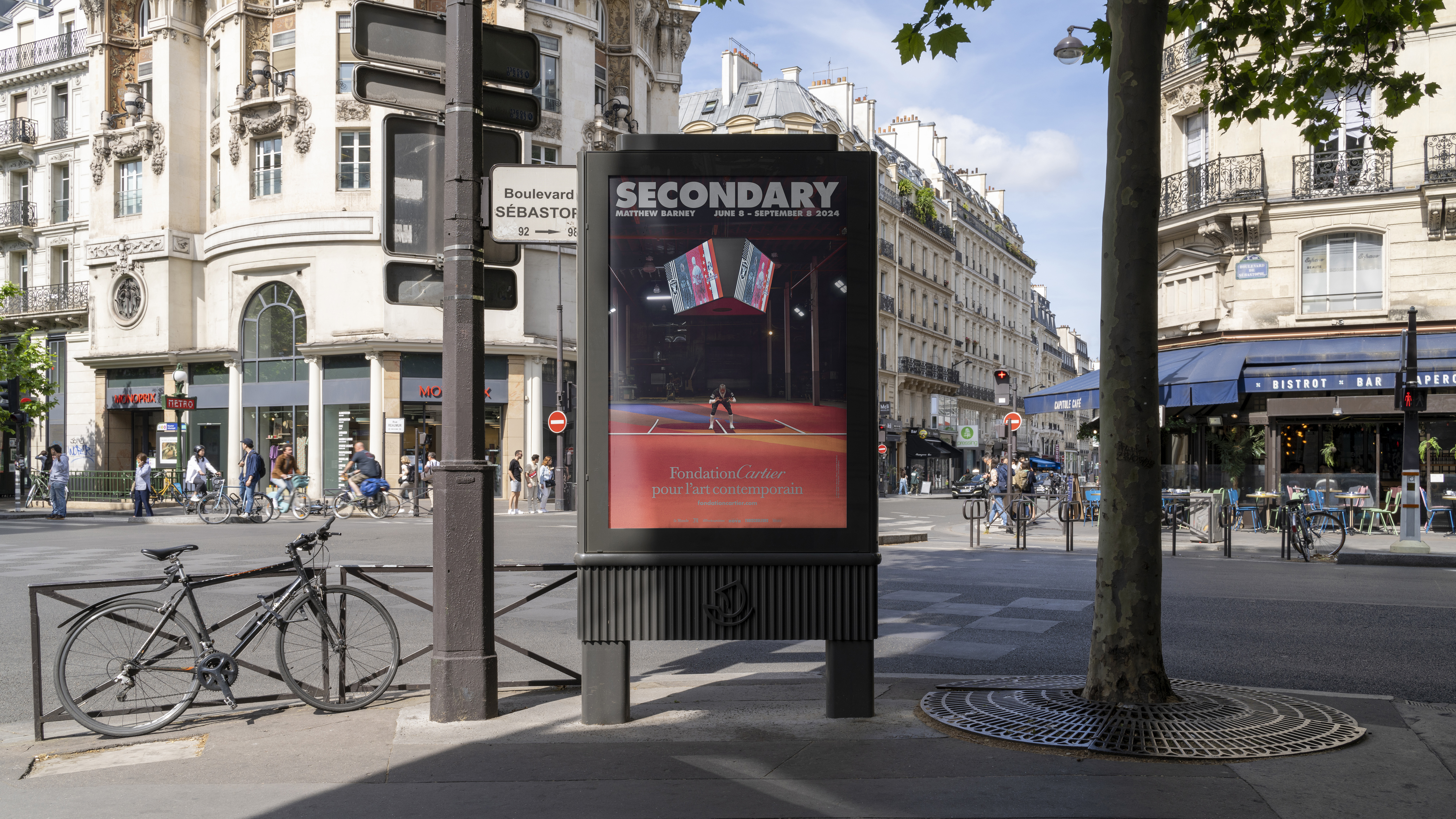 Image of a poster on the street in Paris. The poster features a man in a football uniform below a jumbotron with the word "Secondary" at the top of the poster.