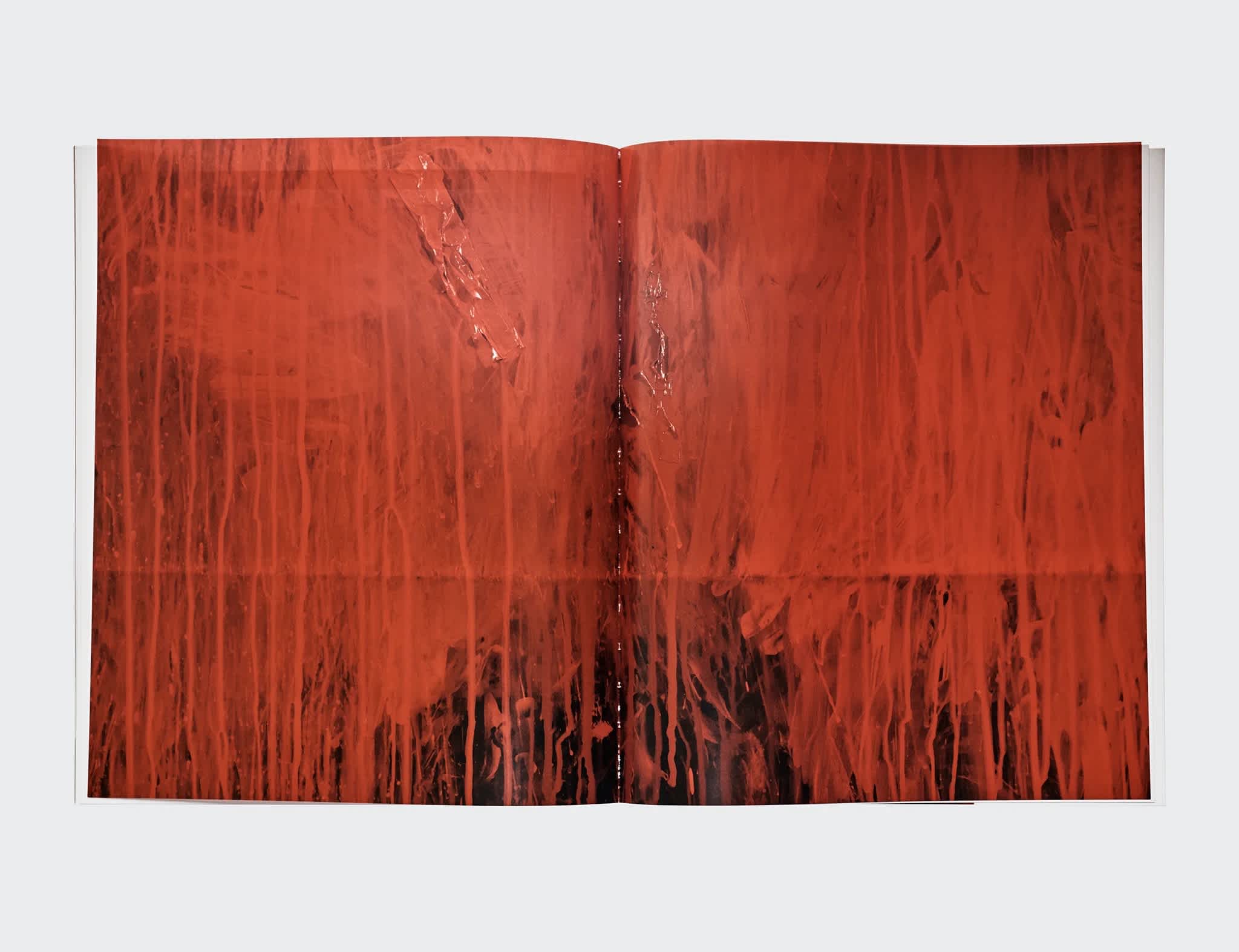 Interior of a book imposed on a white background. The left and right pages feature a centerfold of the painter Reginald Sylvester II's red abstract painting.