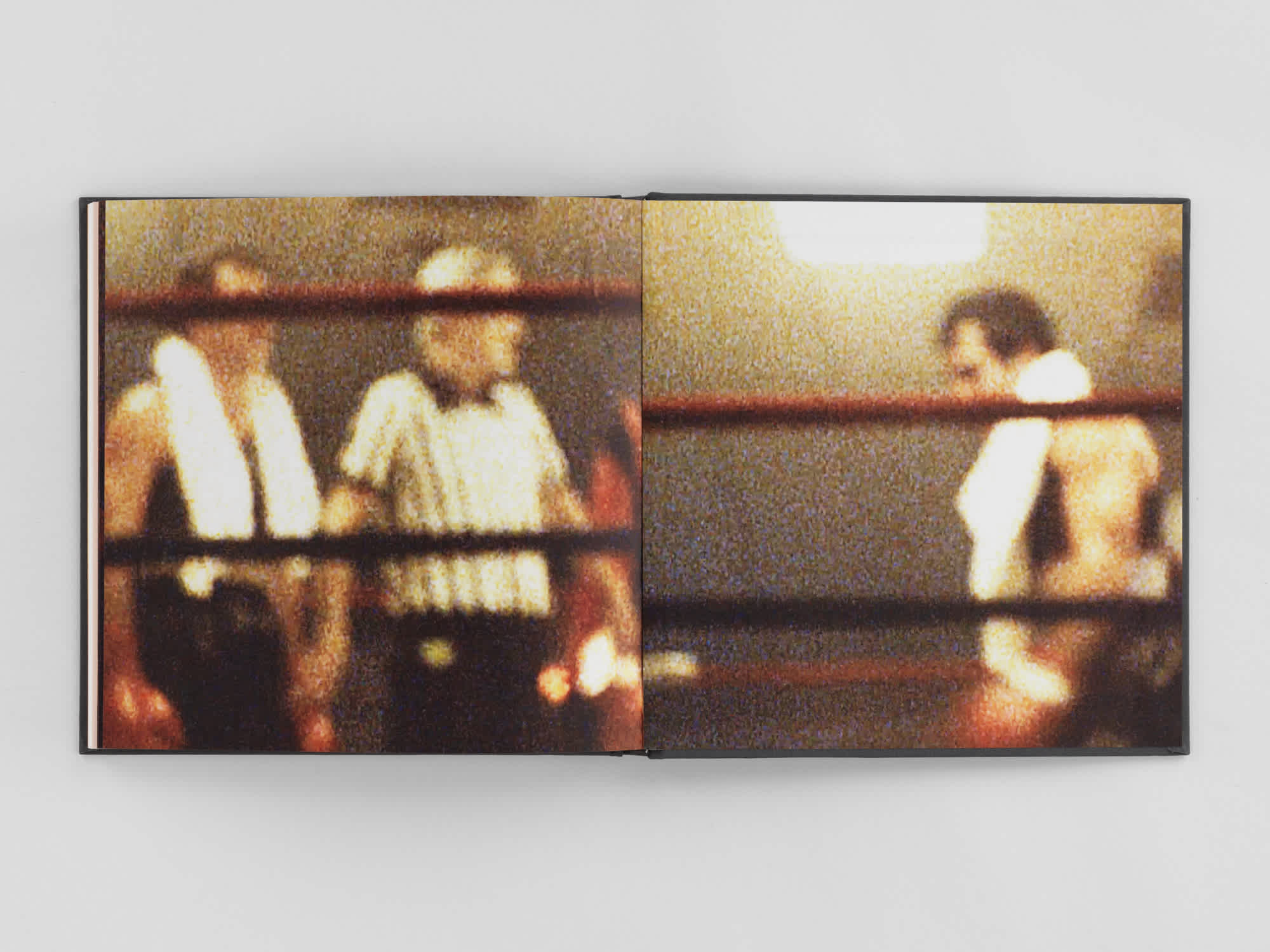 Open book with a grainy, full-bleed photograph of two boxers and a referee in the ring.