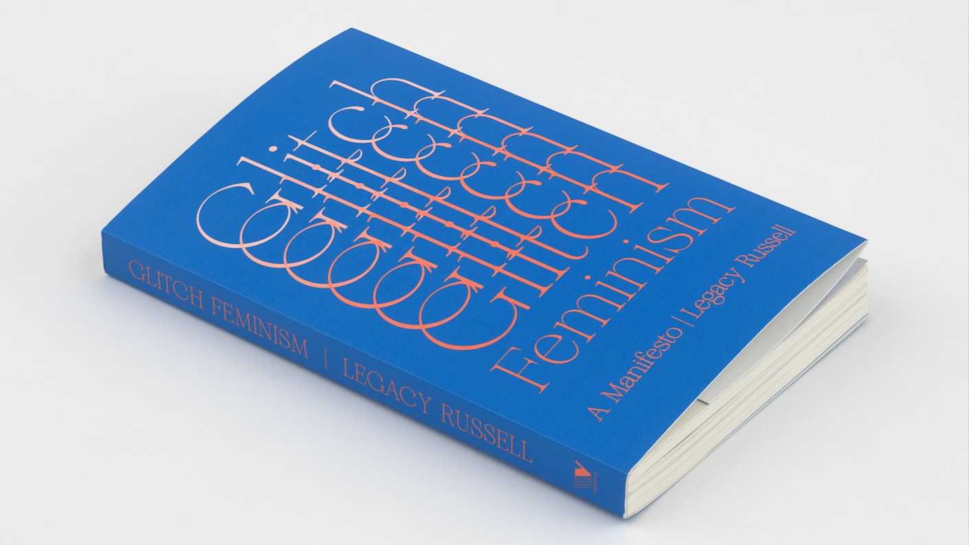 Dark blue book laying flat so the front cover and spine are visible. The word "Glitch" slides from top to bottom in a repeating pattern. The word "Feminism" is just below this followed by "A Manifesto" and the author, Legacy Russell's name. The text is printed in a white to peach gradient.