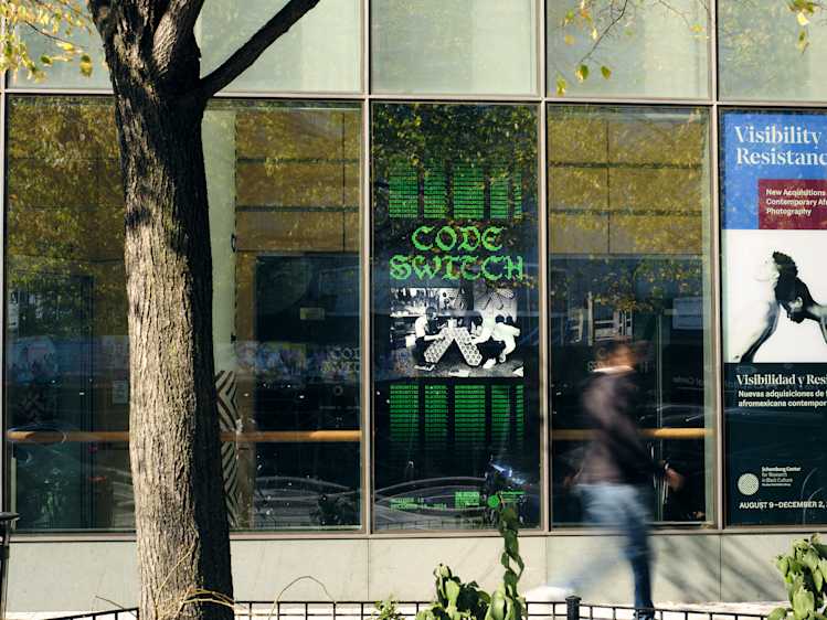 Man walking past building with exhibition poster behind him