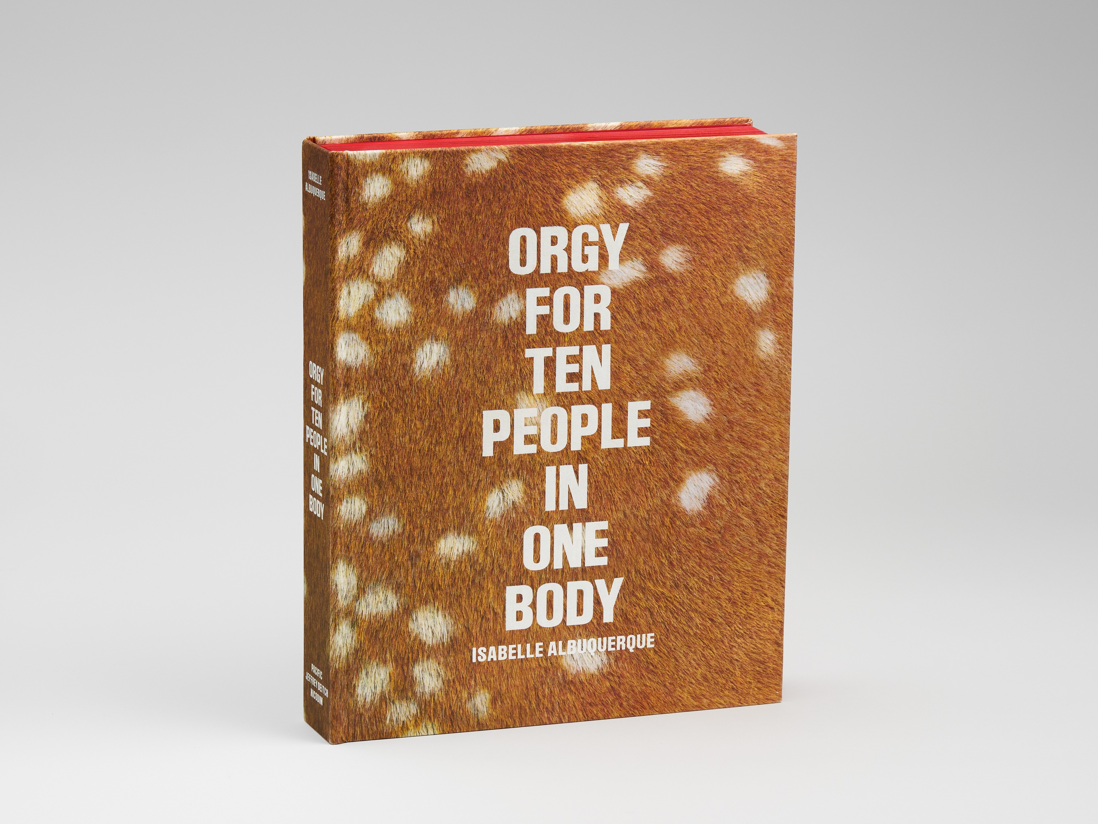 Upright book with speckled fawn print cover and center justified title-column. The edges of the pages, visible at the top of the book are red.