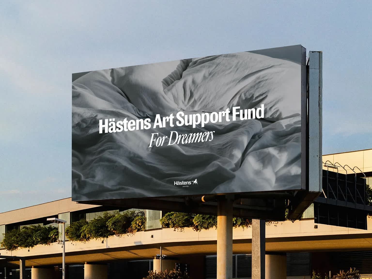 Billboard showing an un-made bed with bold white letters overtop it.