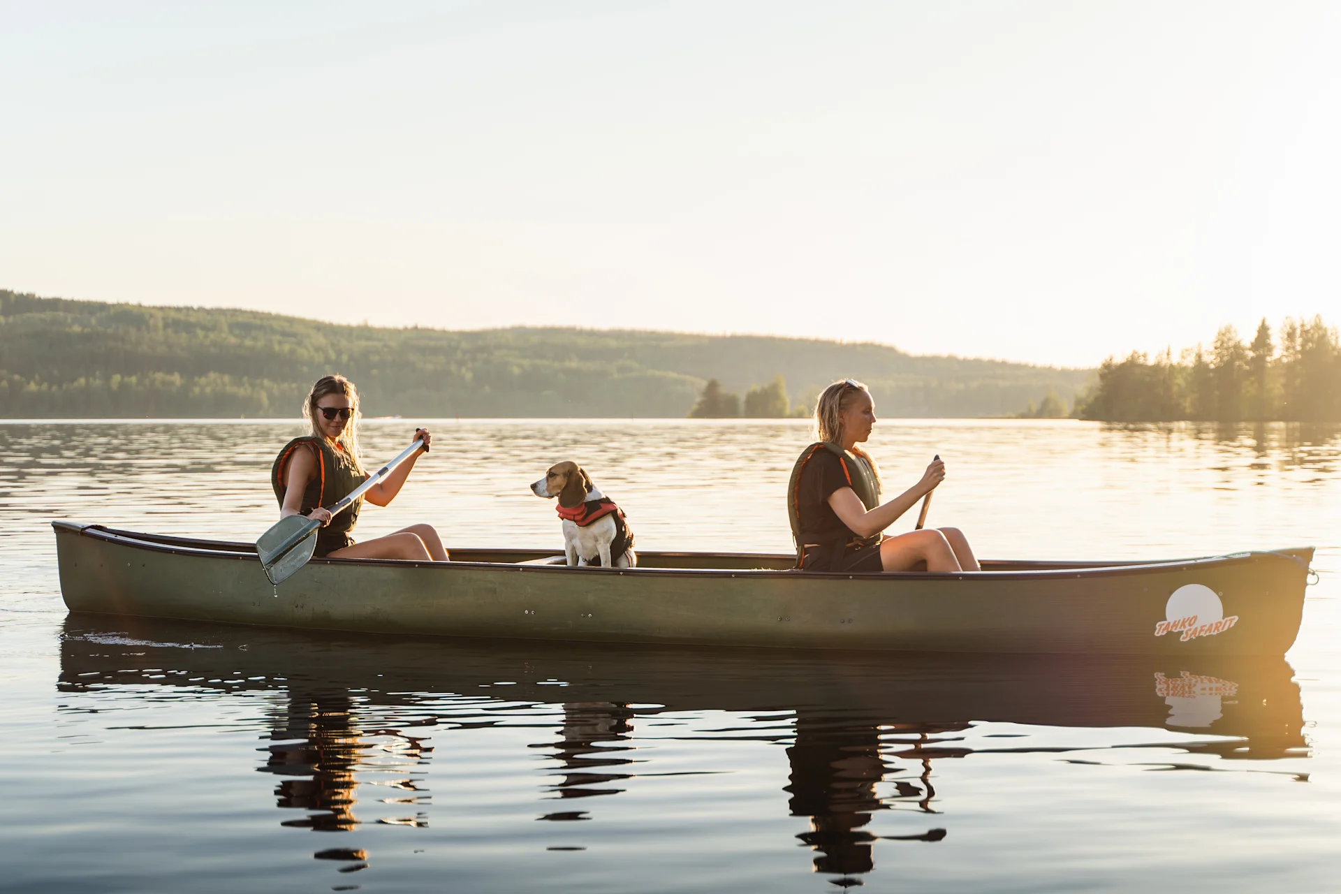 Two womend and a dog in a canoe on a lake