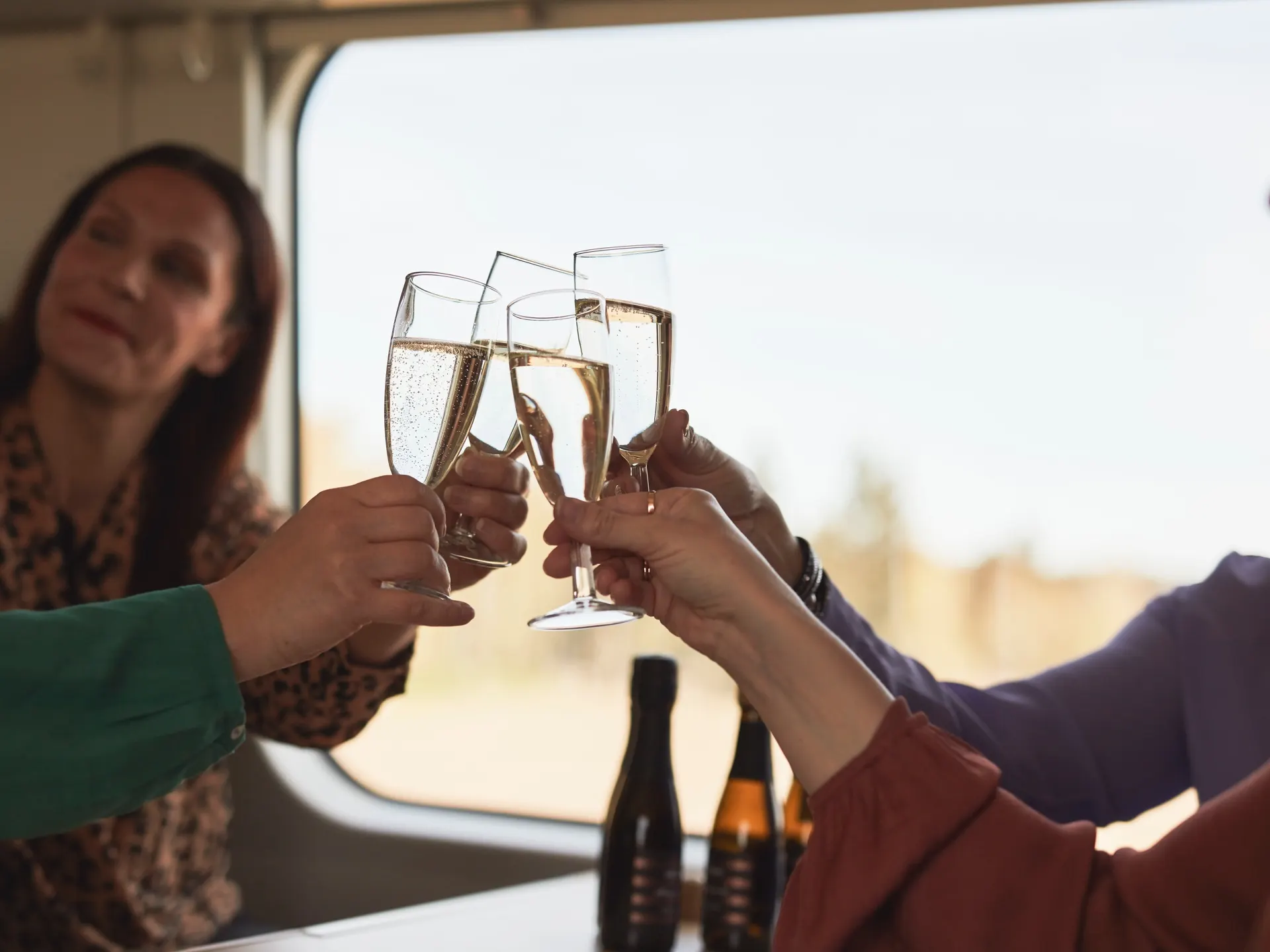 A group is having refreshments, such as sparkling wine and coffee, in the restaurant car.
