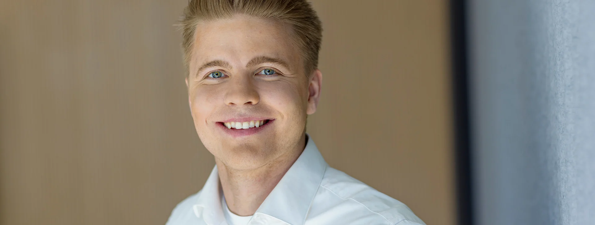 Mies hymyilemässä valkoisessa paidassa. Kuvassa DNA:n vastuullisuuspäällikkö Samu Malmelin.