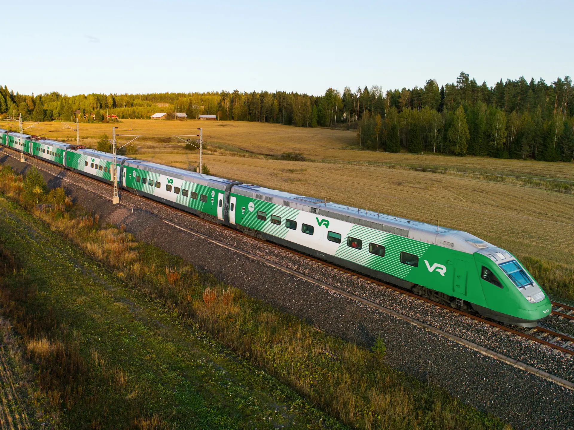 Pendolino Plus train flying through an autumnal field landscape. The wraps on the train reflect VR’s new design. The visual look of the train features green and white stripes running diagonally along the vehicle body.