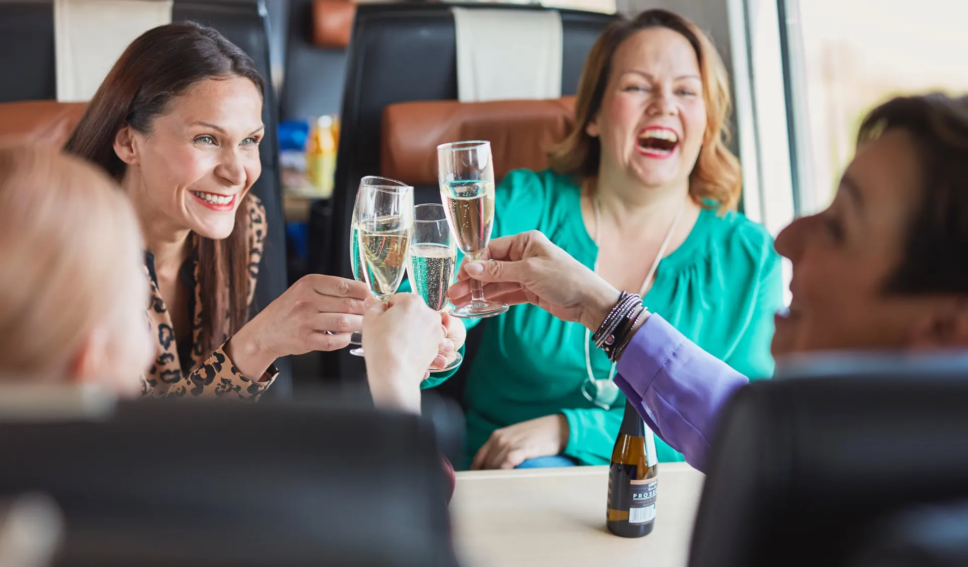 A cheerful group is toasting with sparkling wine in the upstairs of the restaurant car.