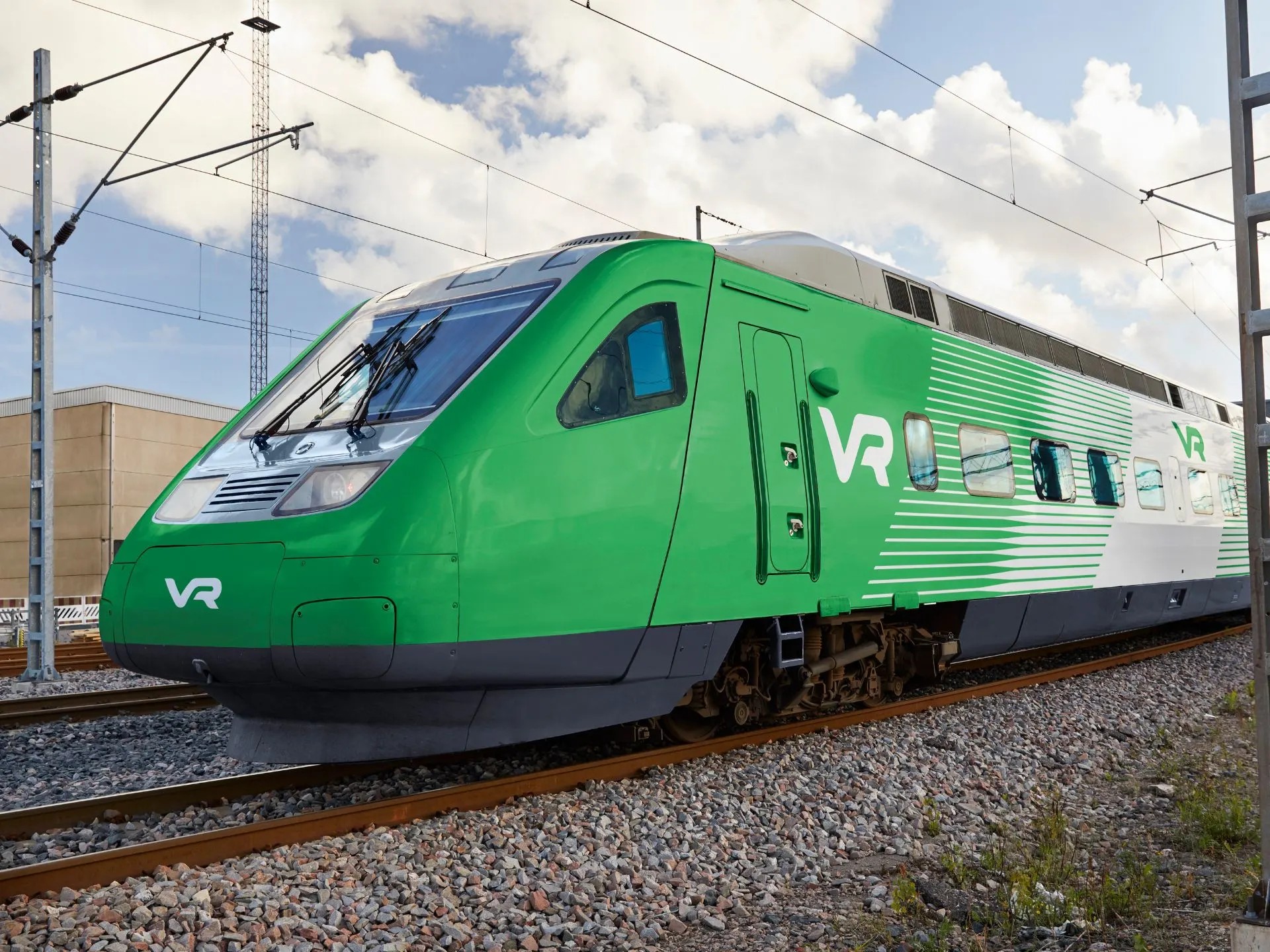 Close-up of the front of the Pendolino Plus train on a depot track section. The front is completely green and has a small white VR logo on the front. The side design features oblique streamlined green and white lines that create a sense of speed.