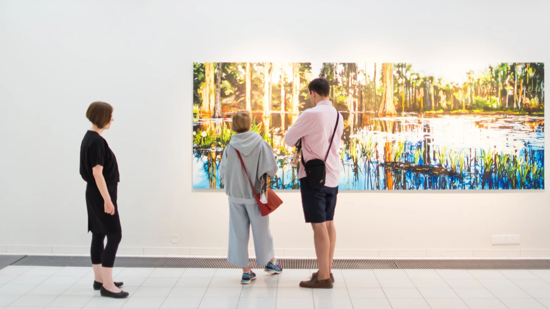 Ihmisiä museossa katselemassa seinällä olevaa maalausta.