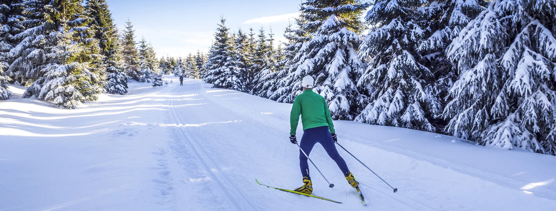 Hiihtäjä hiihtoladulla aurinkoisena päivänä.