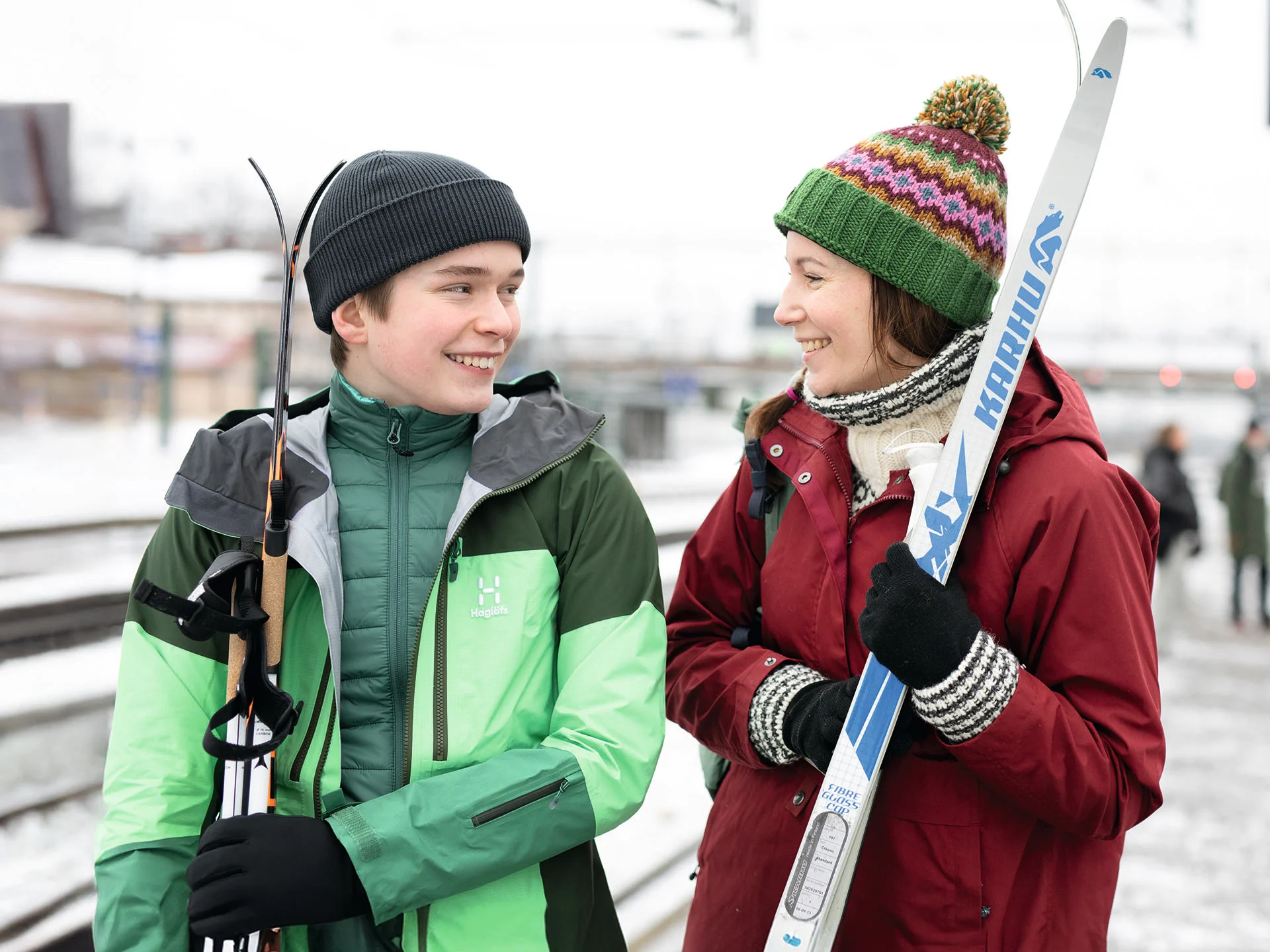 Två personer med skidor på en tågperrong.