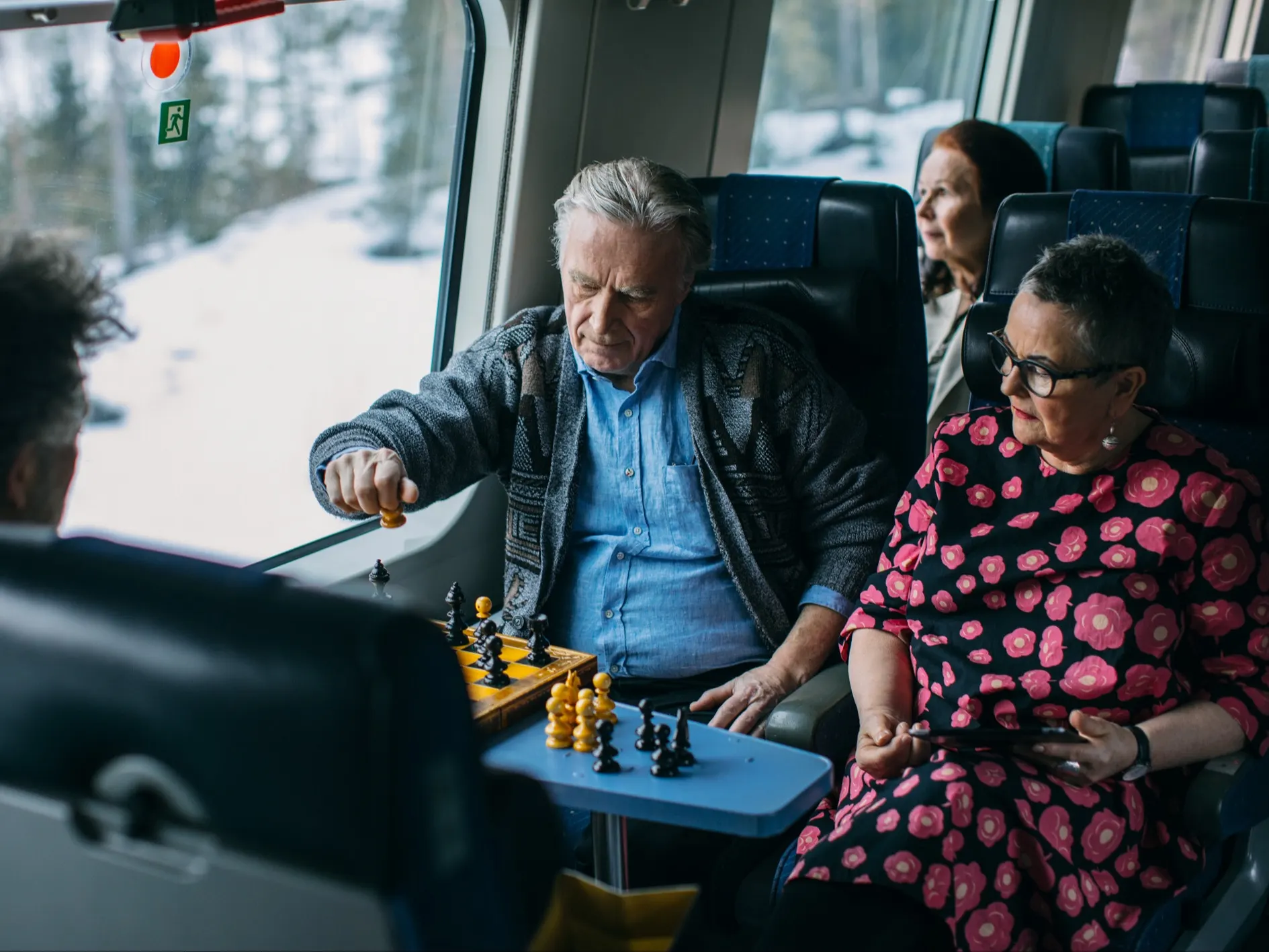 Pensioners are playing chess on a long-distance train.