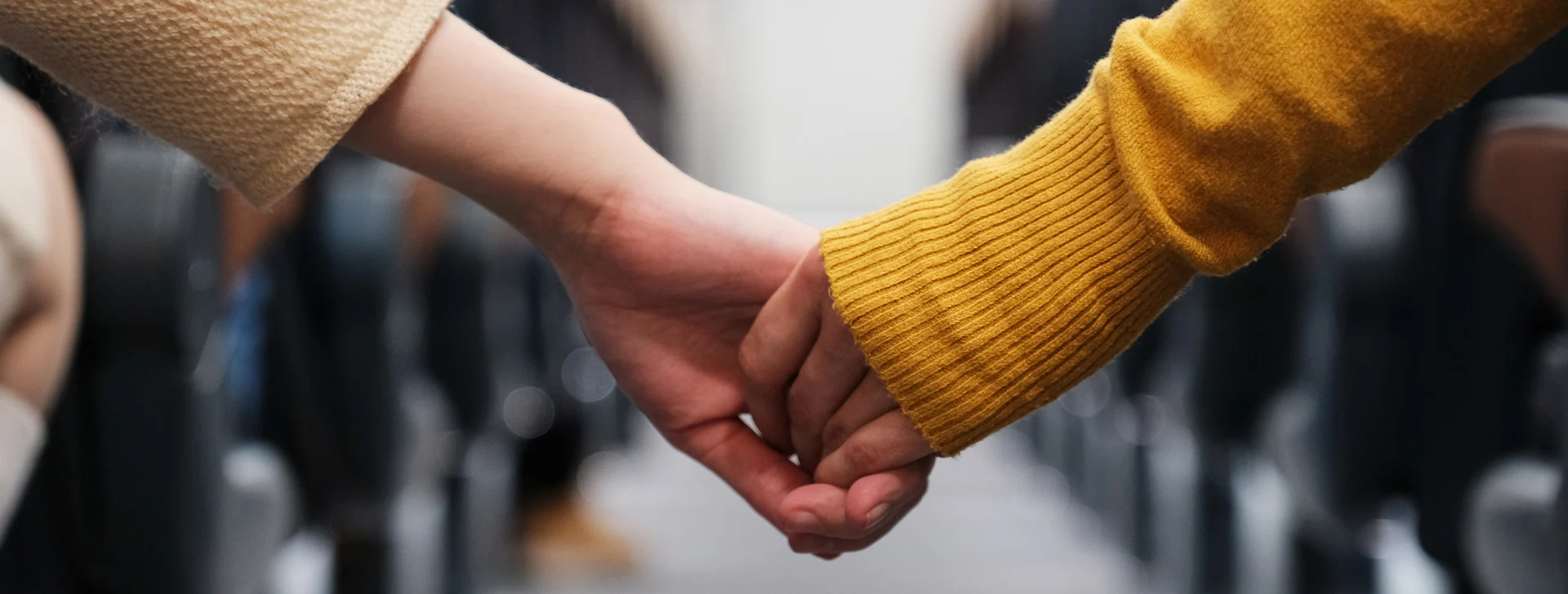 Miniloma pariskunnalle-blogitekstin kuva, jossa kaksi henkilöä pitelee toistensa käsistä kiinni junassa.