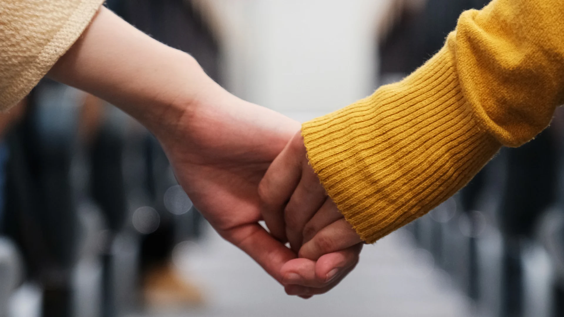 Miniloma pariskunnalle-blogitekstin kuva, jossa kaksi henkilöä pitelee toistensa käsistä kiinni junassa.