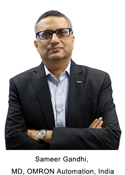 Portrait of Sameer Gandhi, MD, OMRON Automation, India, a professional man wearing glasses and a dark suit jacket over a light patterned shirt, with his arms crossed.