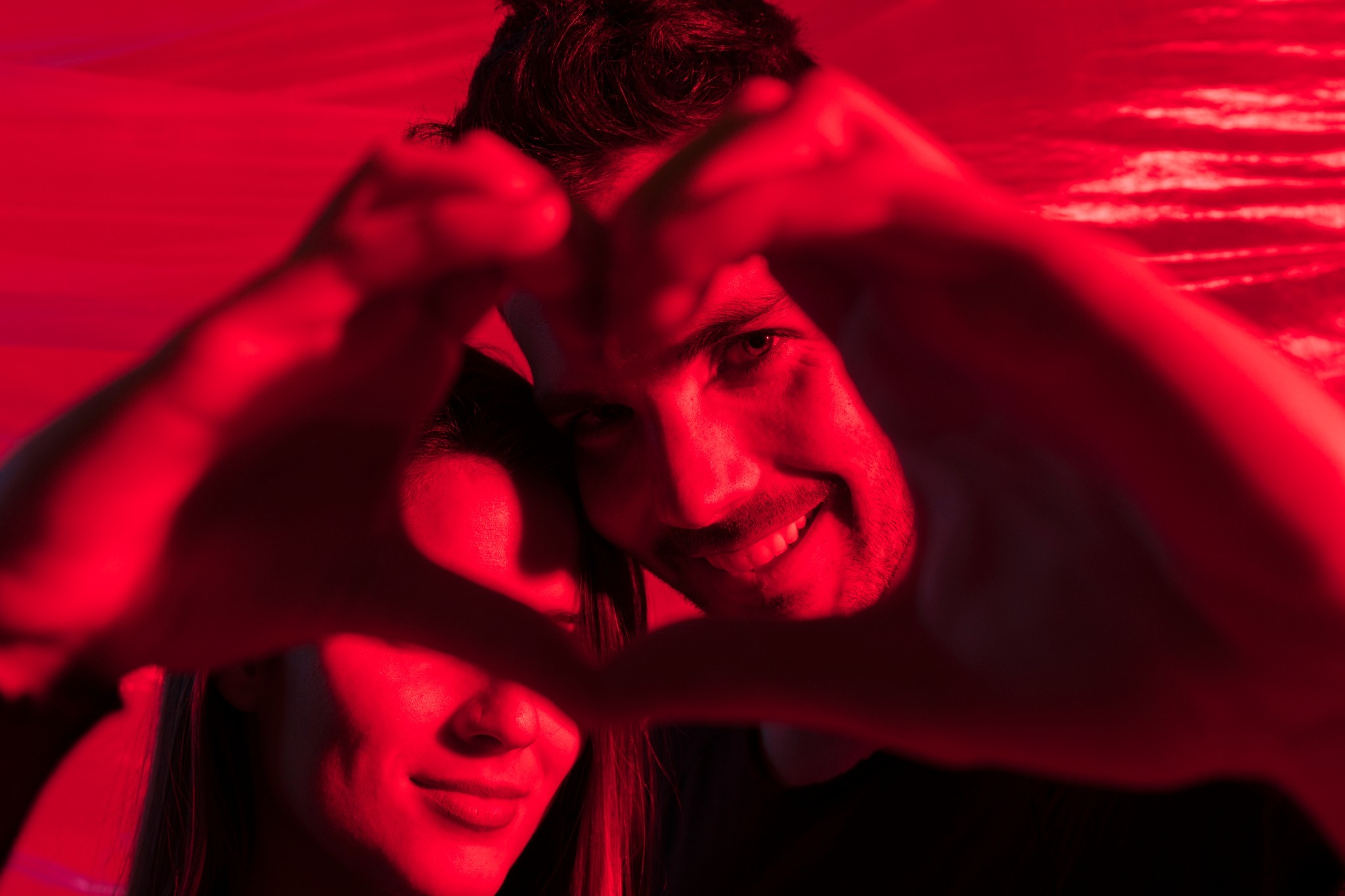 La imagen en color rojo de una pareja formando un corazón con sus manos 