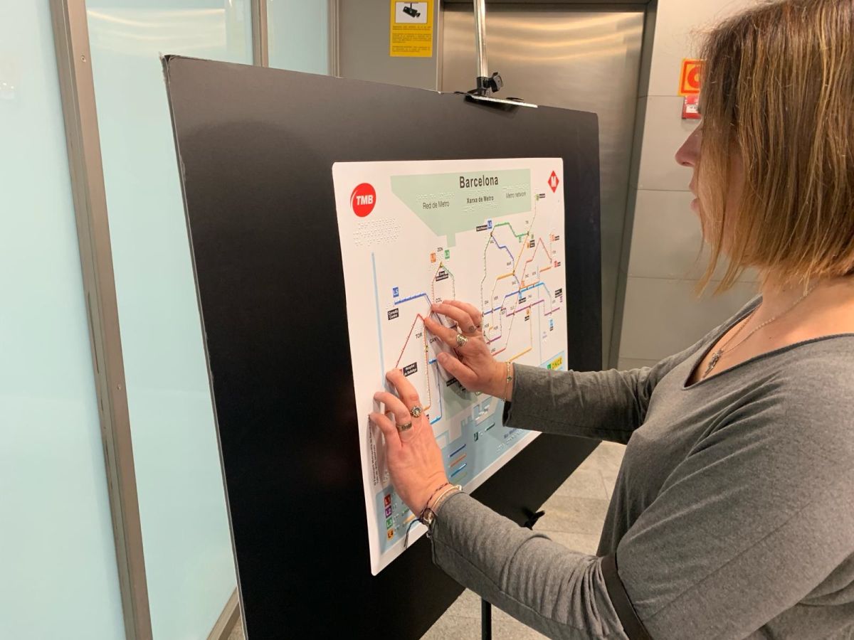 Una joven ciega toca el mapa del Metro de Barcelona accesible.