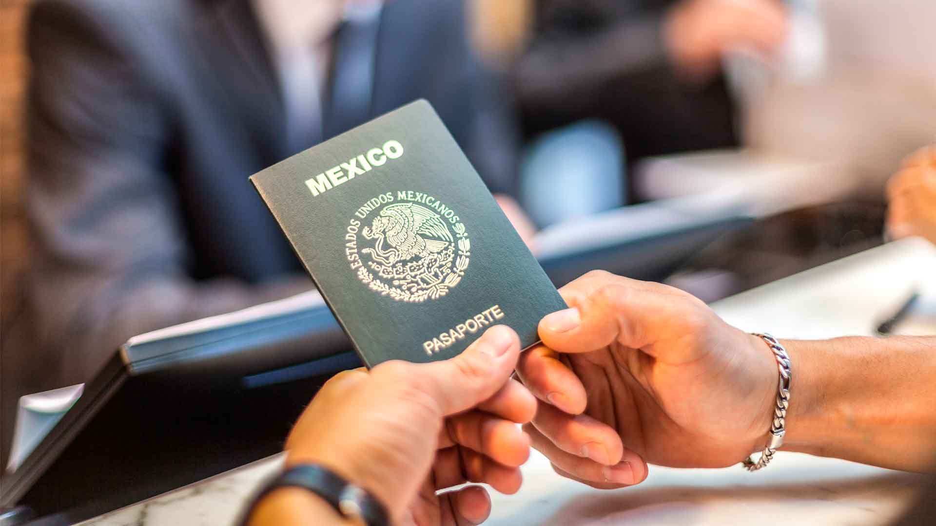 Manos de una persona sosteniendo un pasaporte mexicano.