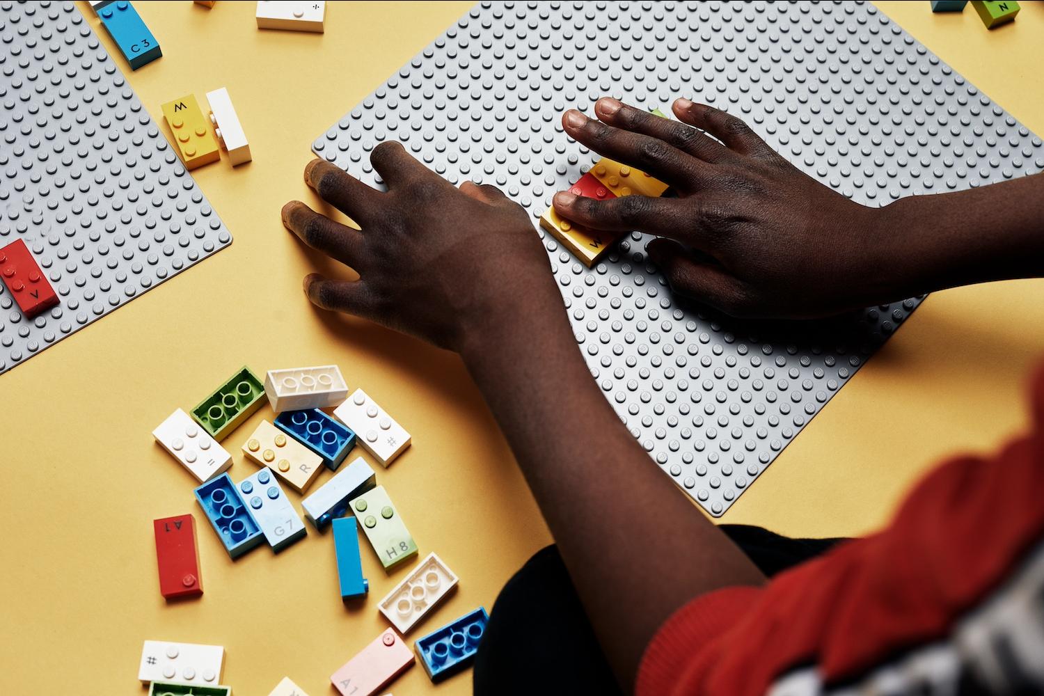 Un niño usa piezas de Lego Braille que tienen tachuelas elevadas que corresponden a una letra o número en braille.