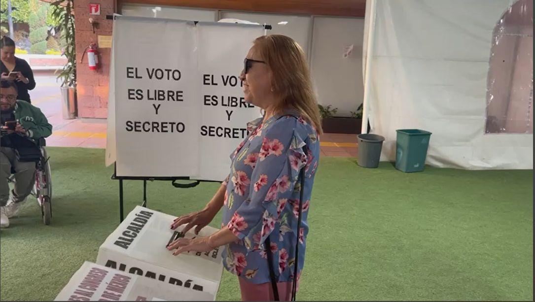 Silvia Lozada, fundadora de la Escuela de Perros Guía y mujer ciega, frente a una urna leyendo en braille.