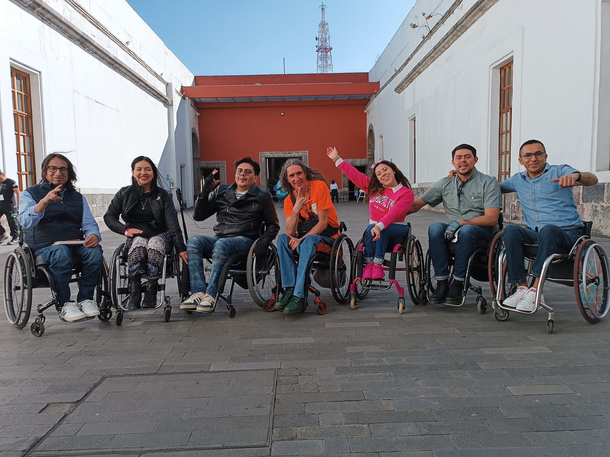 Conjunto de siete personas en silla de ruedas sonriendo mirando a la cámara.