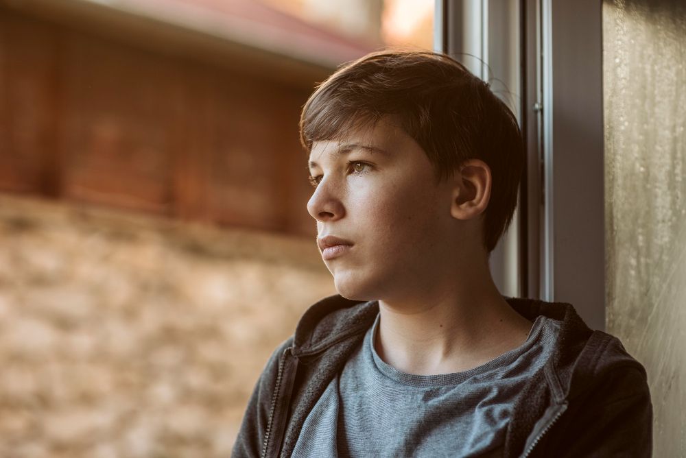 Un joven con autismo mira por la ventana

