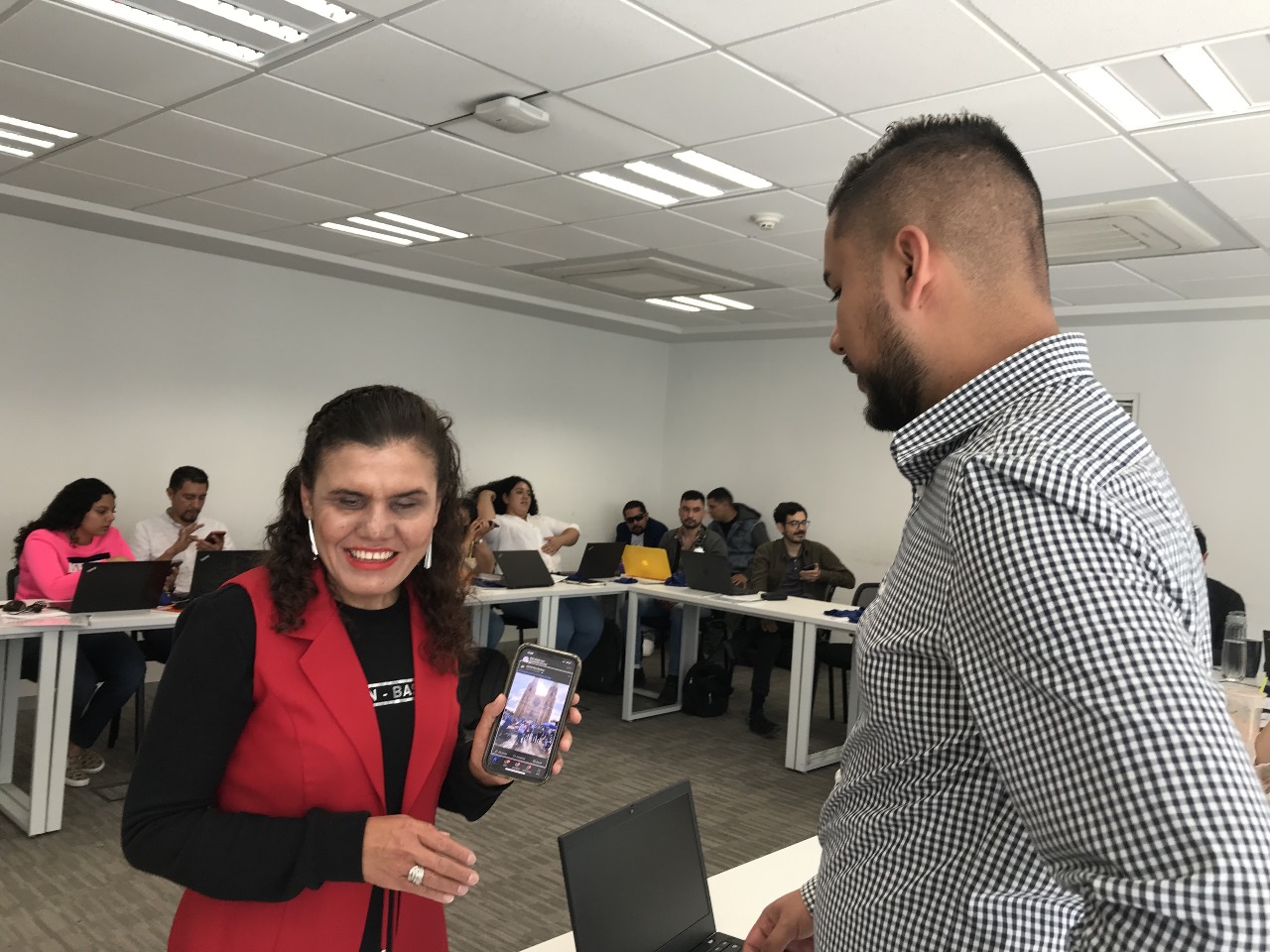 Eneida Rendón sonriendo mientras muestra la pantalla de un teléfono.