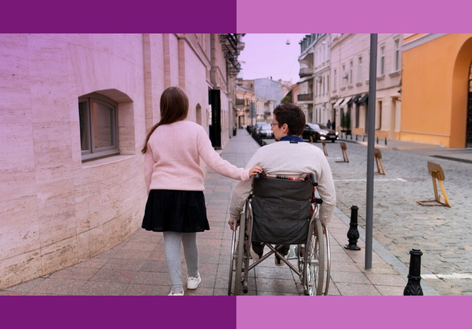 Una mujer (a la izquierda) junto a un hombre en silla de ruedas (derecha) de paseo por la calle.