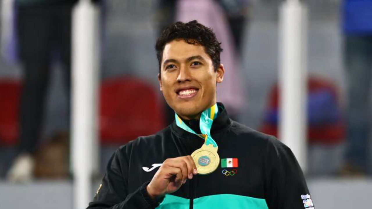 Carlos Sansores sonriendo sosteniendo una medalla colgada en su cuello.