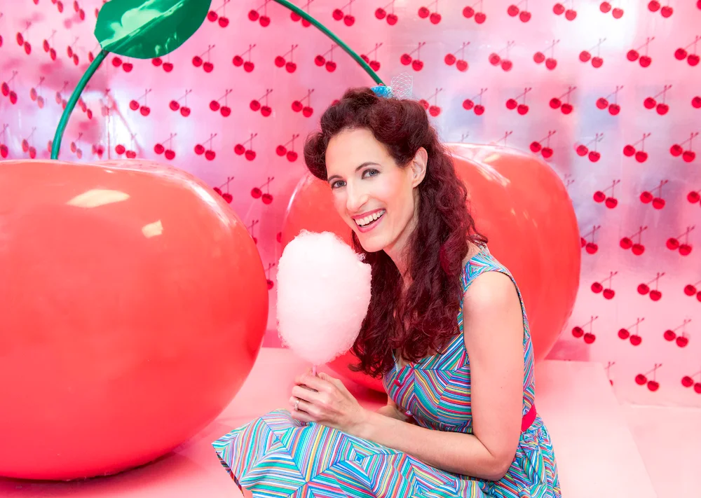 Lisa Sniderman posa sonriente sosteniendo un algodón de azúcar con ambas manos.