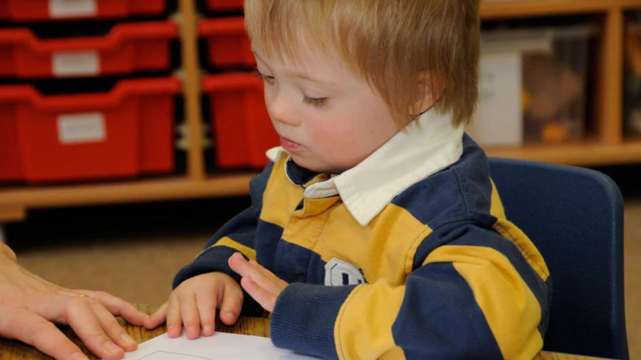 Niño con síndrome de Down leyendo.