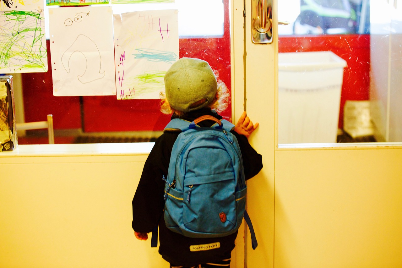 Niño de espaldas a punto de entrar a un salón de clases