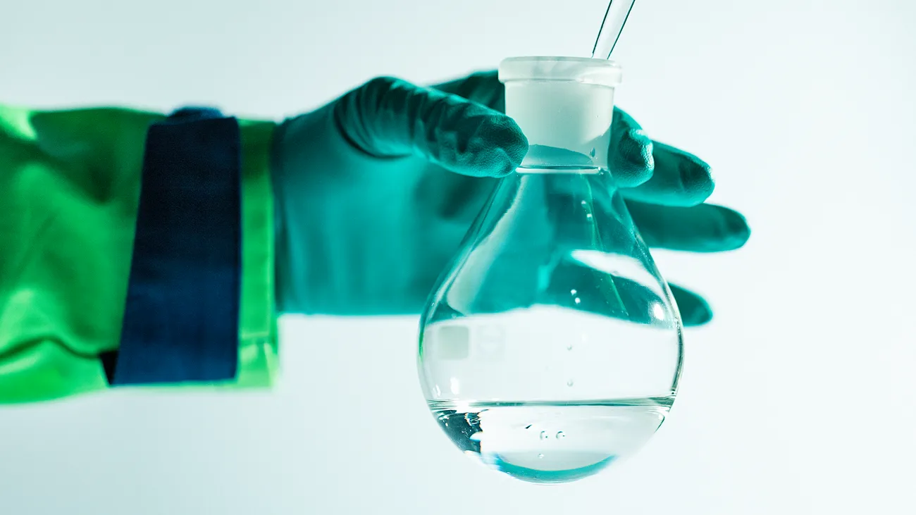 A hand holding a laboratory bottle