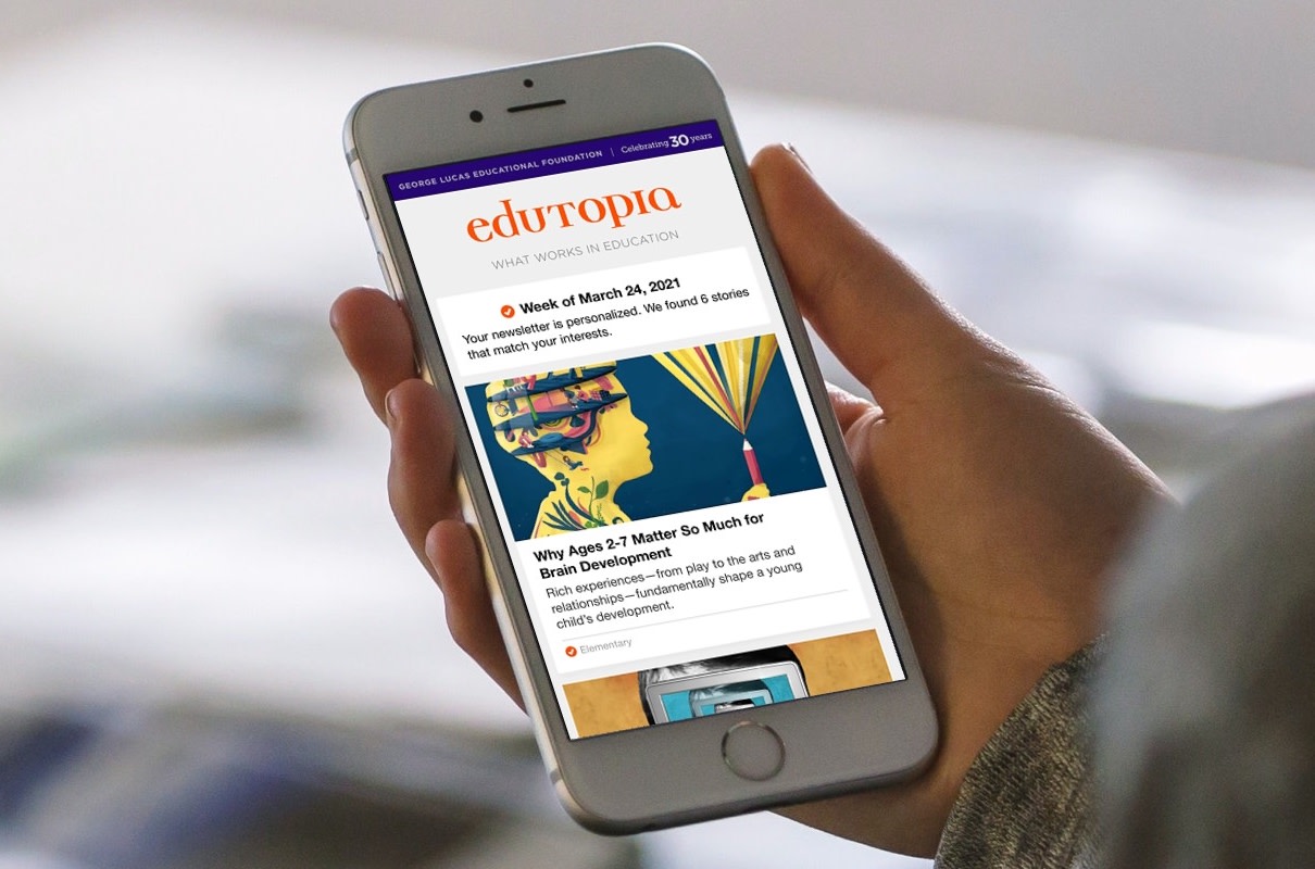 Hand holding a mobile phone that shows the Edutopia Weekly newsletter