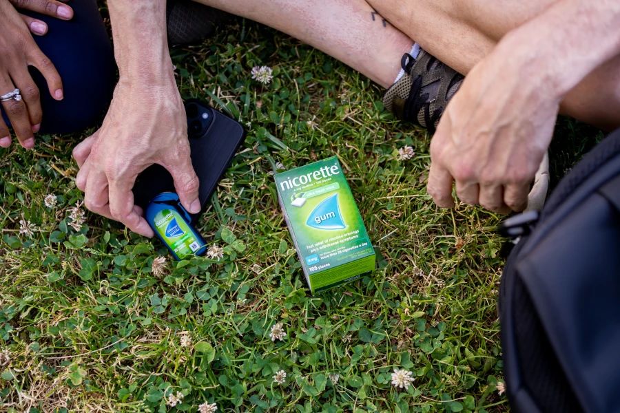 Homme qui dépose une boîte de pastilles NICORETTE et une boîte de gomme NICORETTE par terre