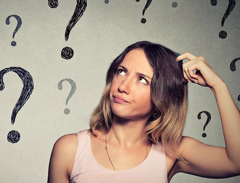 Une femme se gratte la tête et regarde vers le haut d’un air interrogatif