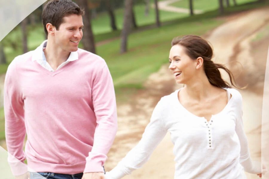 Couple heureux marchant ensemble dans le parc en se tenant la main et en souriant
