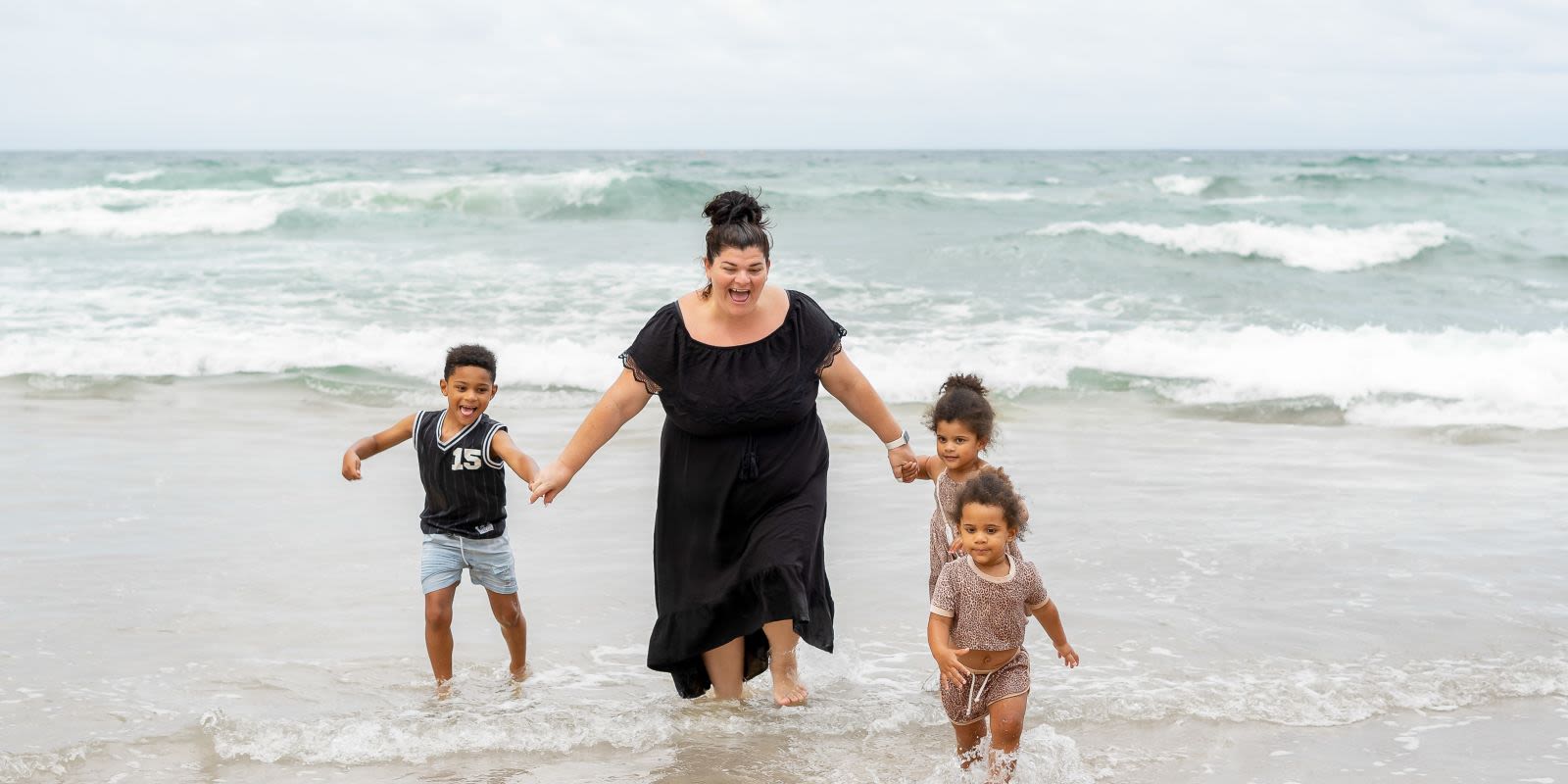 Woman and three children playing in the sea