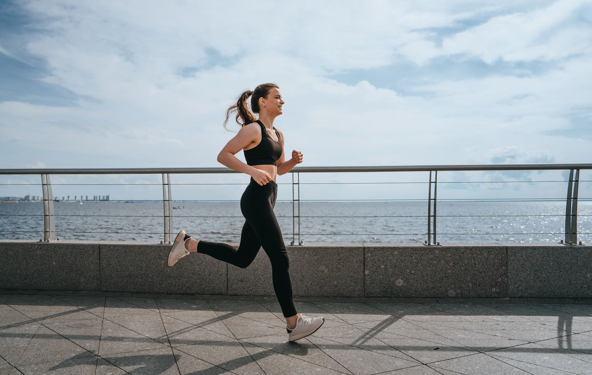 Woman running along promenade with blue sky