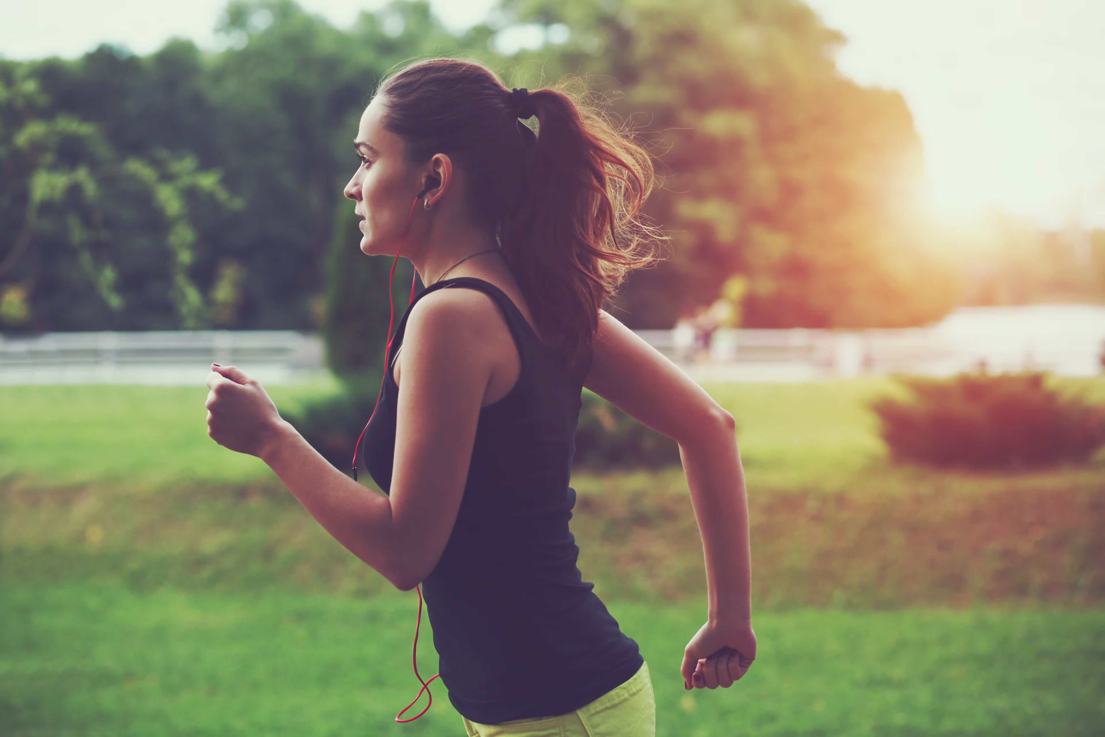 femeie sportivă alergând în parc la lumina soarelui răsărit