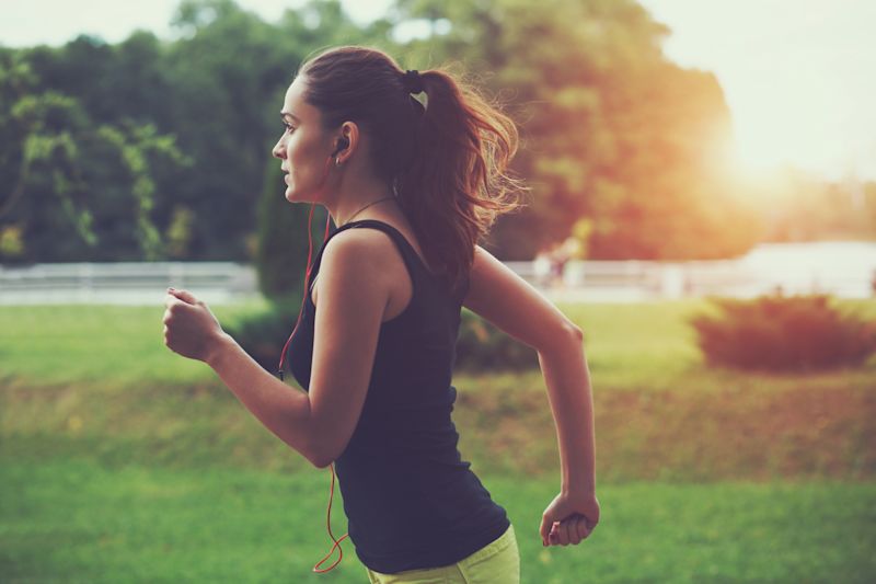 femeie sportivă alergând în parc la lumina soarelui răsărit